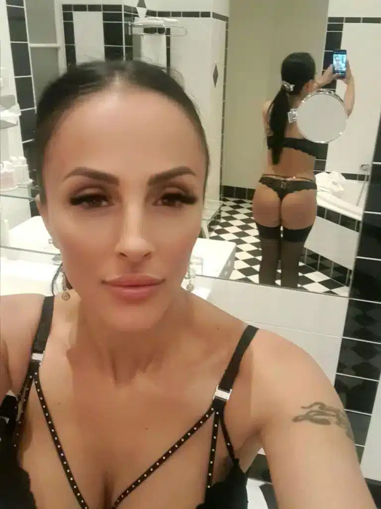 Alexia in Dessous macht in einem Badezimmer ein Selfie.