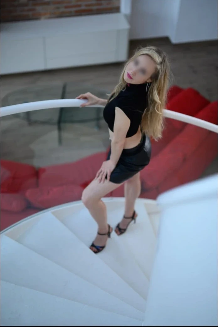 Anna in schwarzer Kleidung posiert auf einer weißen Wendeltreppe.