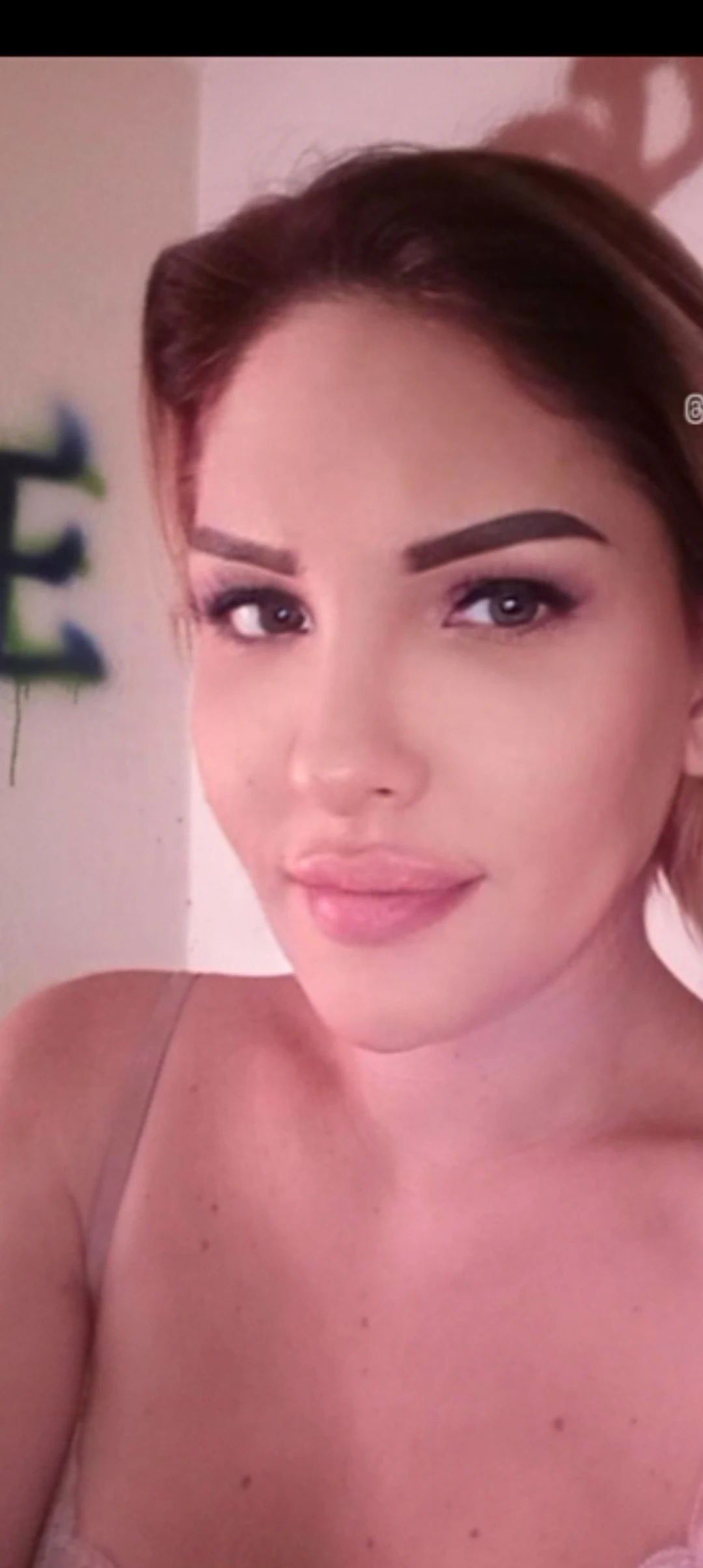 Escort Wien Anna heller Haut, langen braunen Haaren blickt in die Kamera und lächelt sanft.