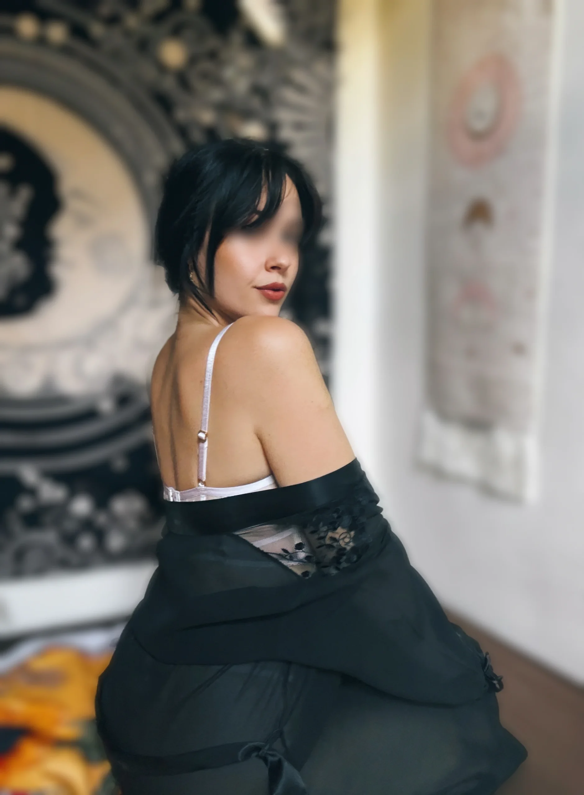 Elena in weissen Spitzen-Dessous kniet auf einem Bett