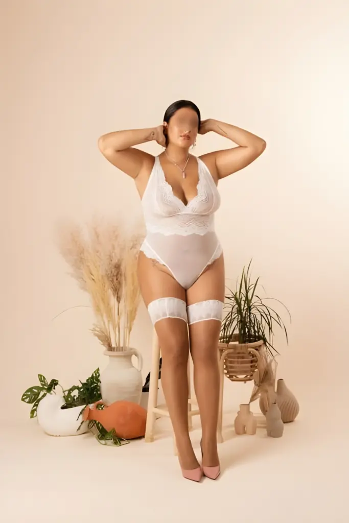 Serena is leaning against a bar stool, wearing a white bodysuit