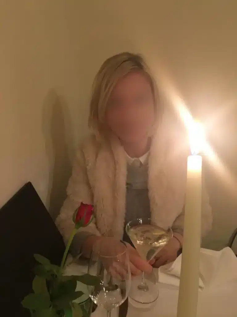 Irina sitzt an einem Tisch mit einem Cocktailglas