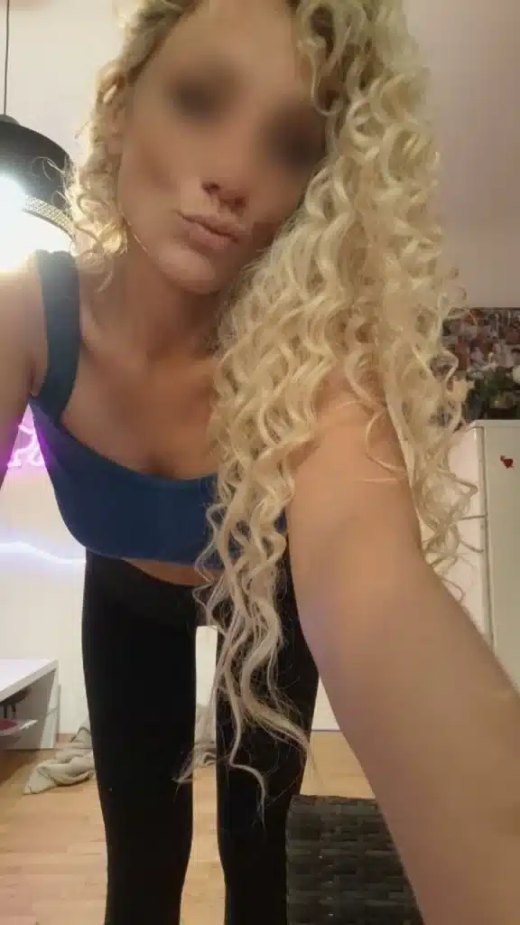 Jessy is posing for the camera in a blue top and black pants.