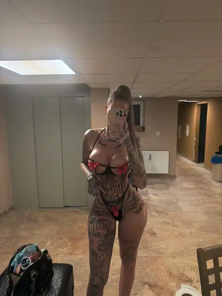 Vanessa, who has numerous tattoos, takes a mirror selfie in a room.