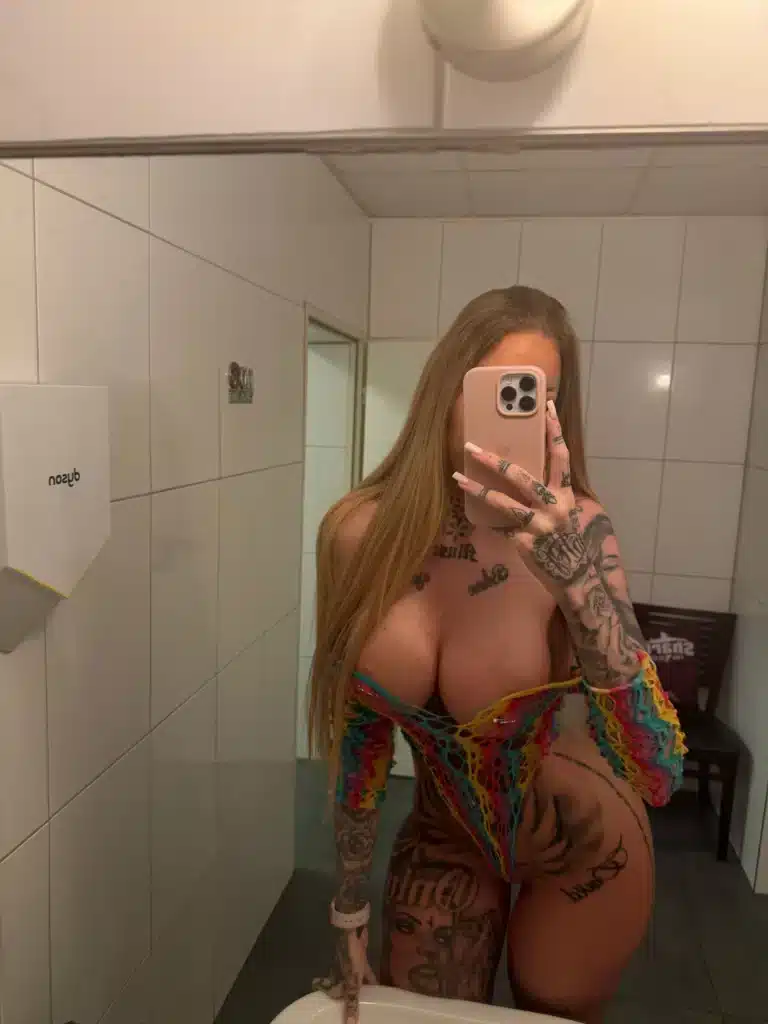 Vanessa, with her long hair, is taking a selfie in front of the bathroom mirror.