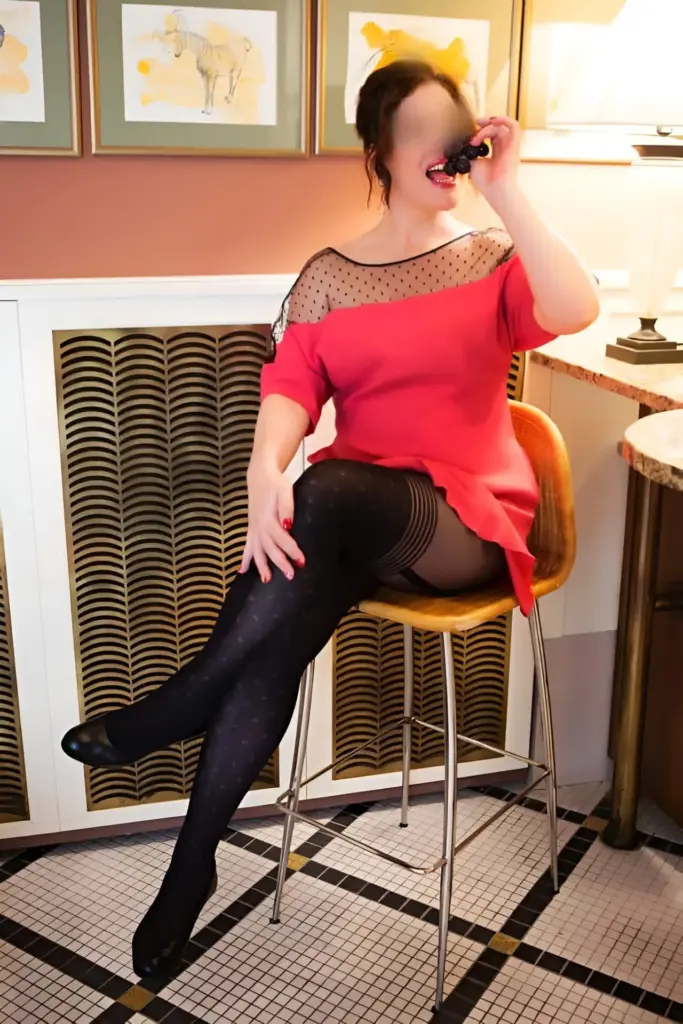 Sandra is also sitting in a chair wearing a red dress