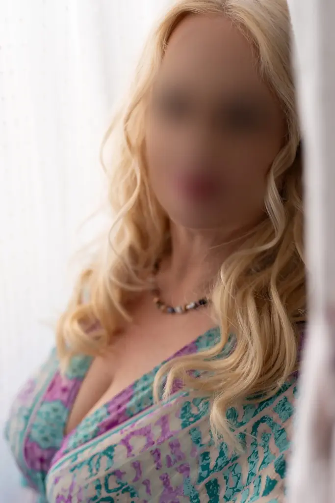 Julietta lehnt an einer Türe, angezogen mit einem türkis buntem Kleid.