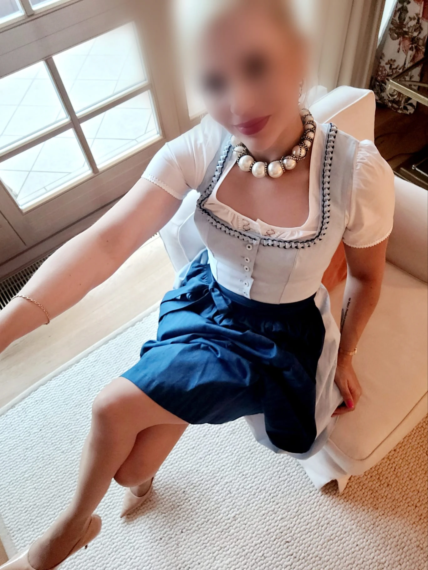 Eva im Dirndl sitzt auf einem Stuhl